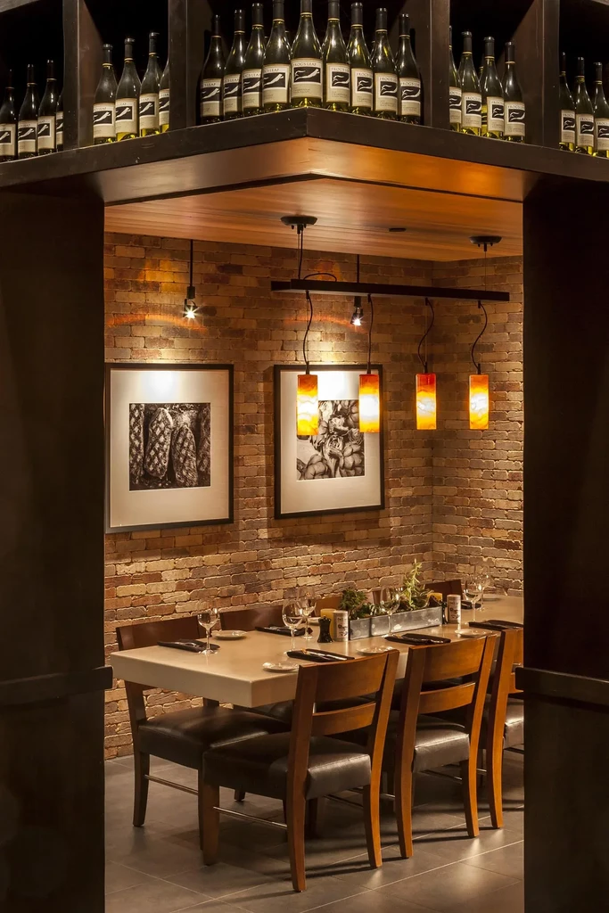 Warm private dining room with wine bottles, set table, brick.