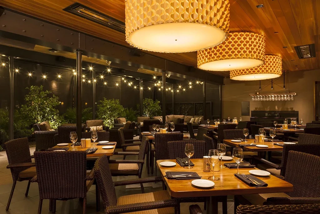 Warm, elegant restaurant dining room with an illuminated outdoor patio.