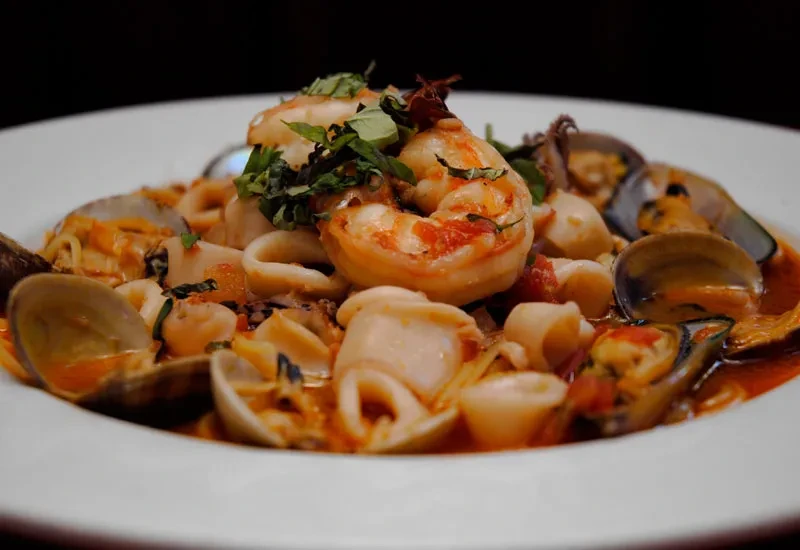 Plate of seafood with shrimp, clams, mussels, and tomato-herb sauce.