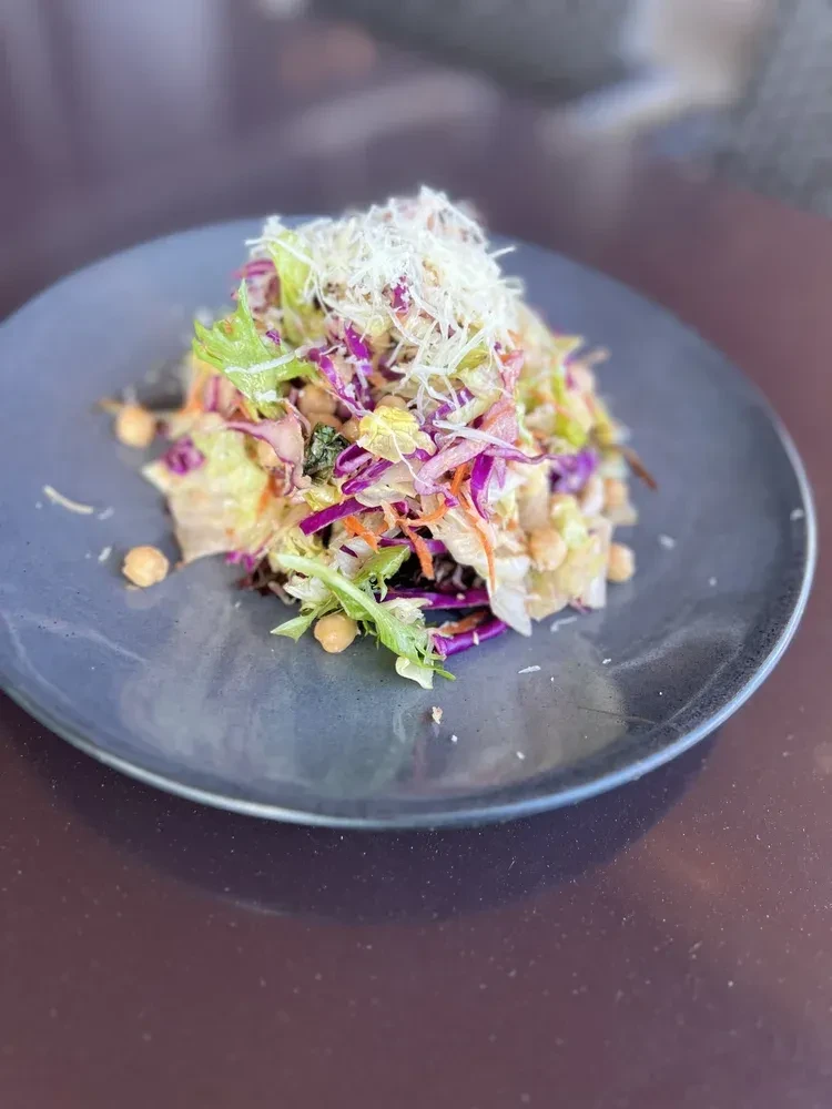 Colorful salad with greens, cabbage, carrots, chickpeas, and cheese.