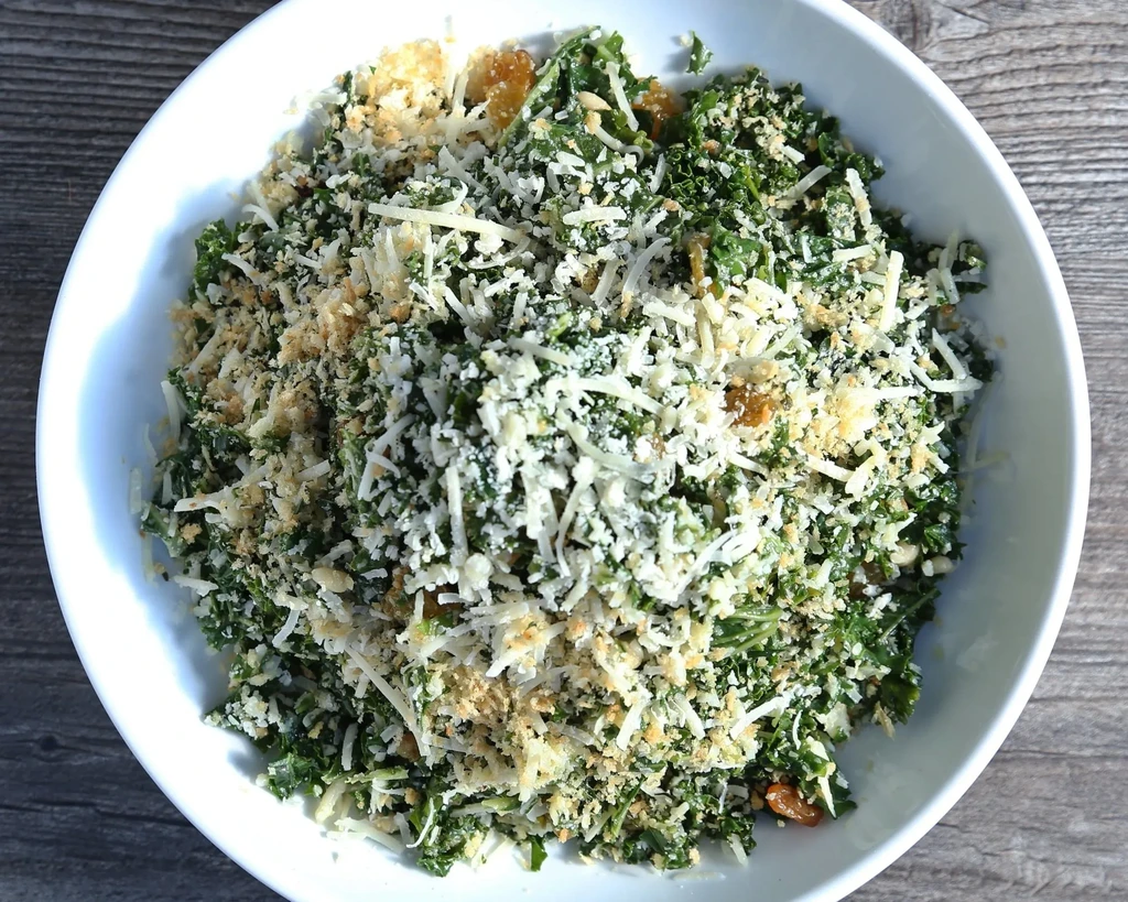 Overhead chopped kale salad with cheese, crumbs, and golden pieces.