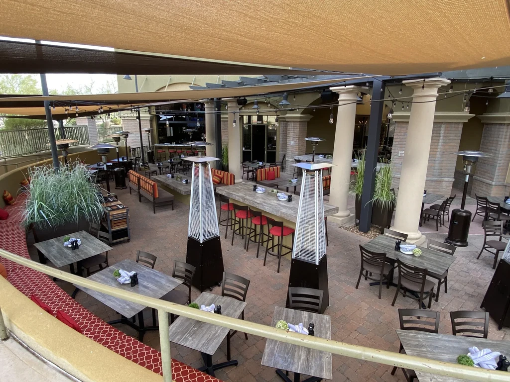 Empty outdoor patio with diverse seating, awnings, and heaters.