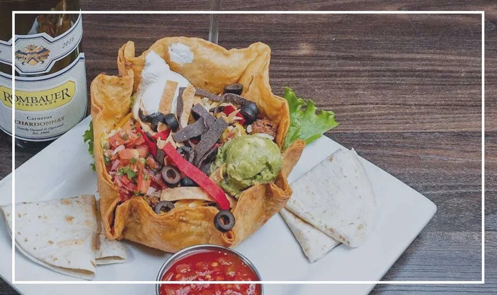 A colorful taco salad served in a crispy tortilla bowl.