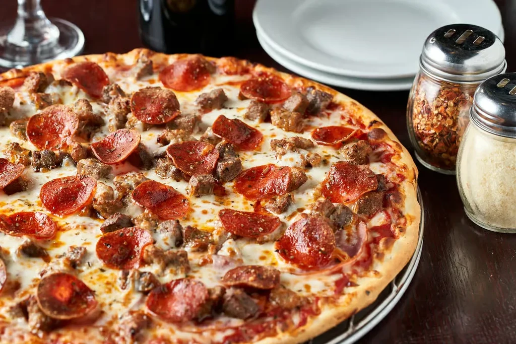 Golden brown pizza with pepperoni, sausage, and melted cheese.