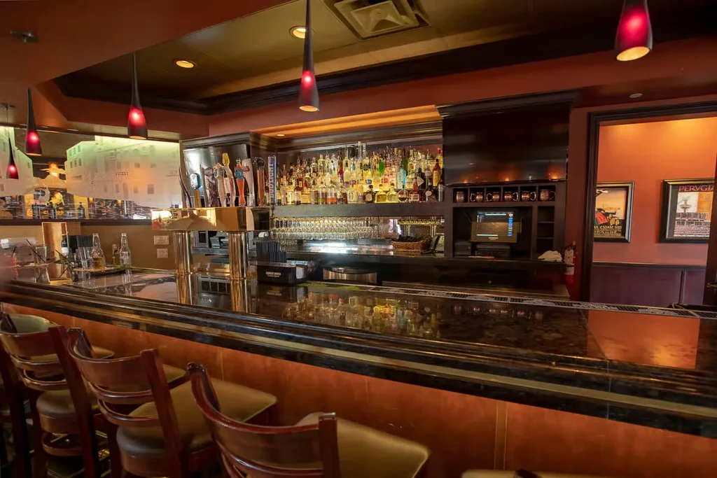Restaurant bar with polished dark counter, stocked shelves, and warm glow.
