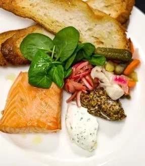 Overhead close-up of salmon fillet with spinach, pickled vegetables, and sauces.