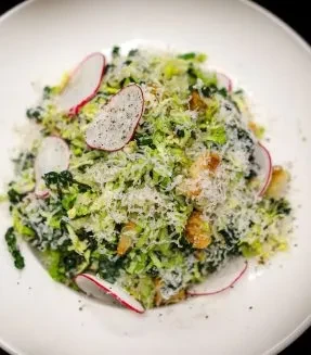 Green salad with grated cheese, radish slices, and golden croutons.