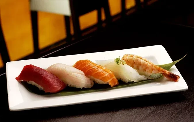 Five neatly arranged, vibrant nigiri sushi pieces on a white plate.