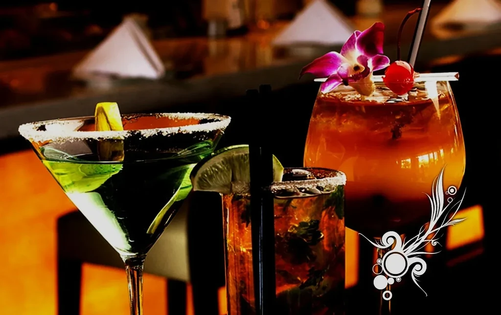 Three colorful, garnished cocktails, prominently displayed against a dark background.