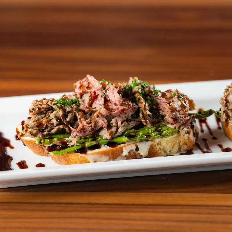 Open-faced roast beef sandwich with asparagus, cheese, and glaze.