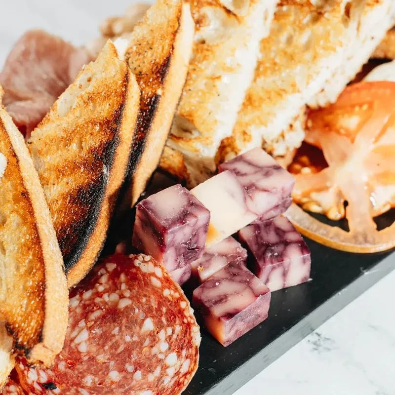 Charcuterie board with grilled bread, marbled cheese, salami, and cured meats.