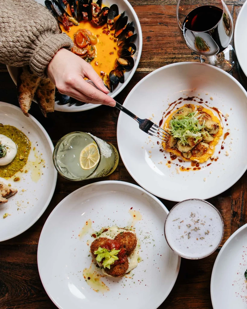 Overhead view of a rustic table with beautifully plated food and drinks.