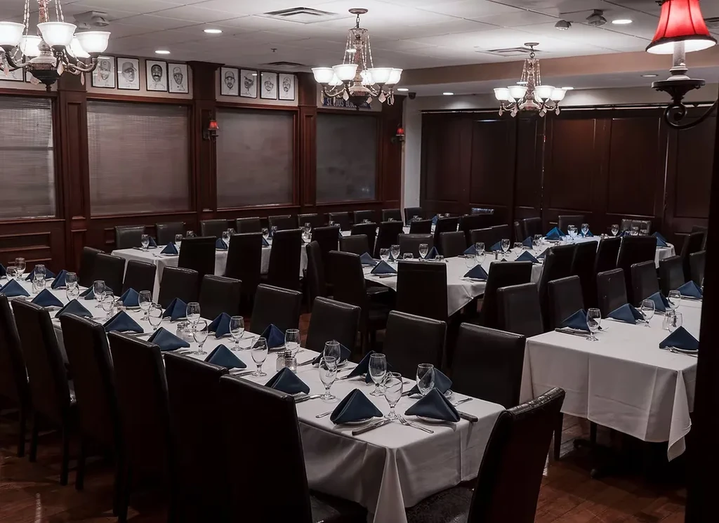 Formal dining room, set tables, wood paneling, chandeliers, St. Louis Blues art.