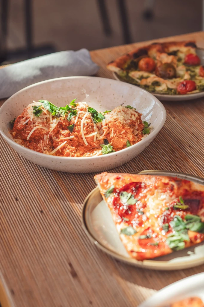 Close-up of Italian dishes: meatballs, pepperoni pizza, and pesto flatbread.