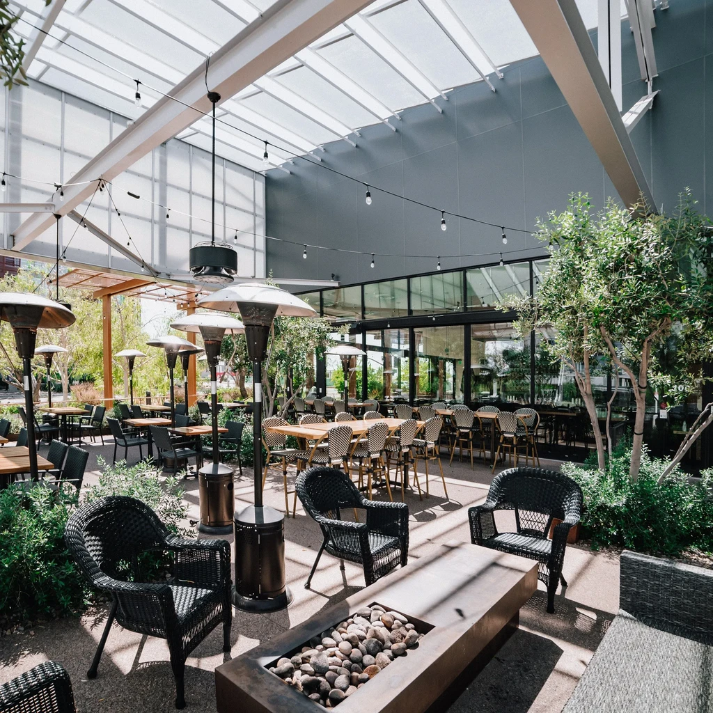 Bright, empty, modern dining patio with fire pit and string lights.