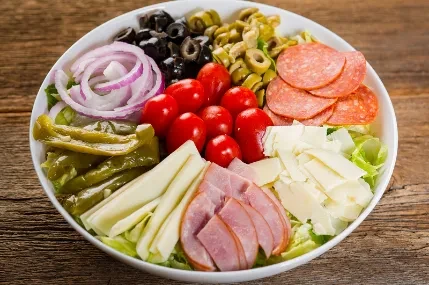Vibrant, arranged deli-style salad with meats, cheeses, and vegetables.