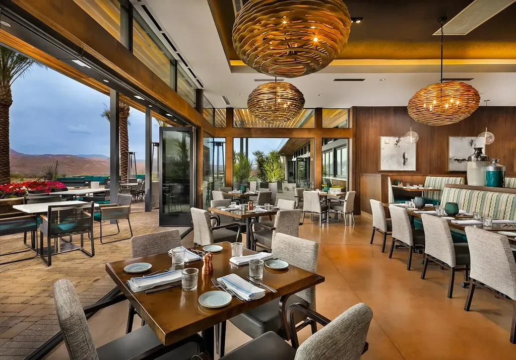 High-end restaurant dining room and patio overlooking desert mountains.