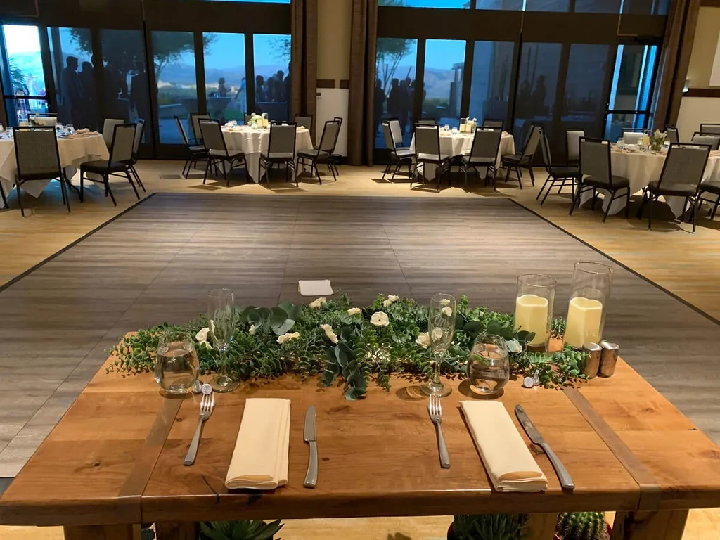Set wooden table for two in a warm, large event hall.