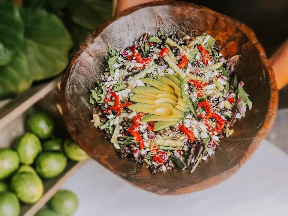 Colorful avocado and black bean salad in a rustic wooden bowl.