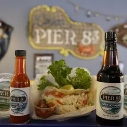 Pier 83 hot sauce, malt vinegar, and a seafood roll with lemon.