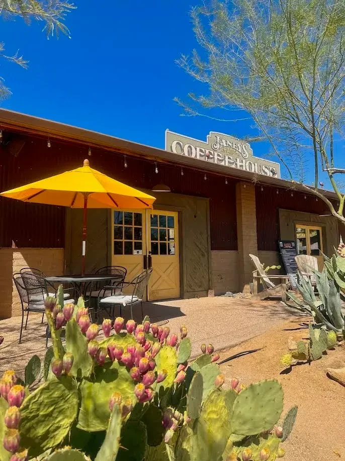 Janey's Coffee House exterior: rustic, sunny, with desert plants and seating.