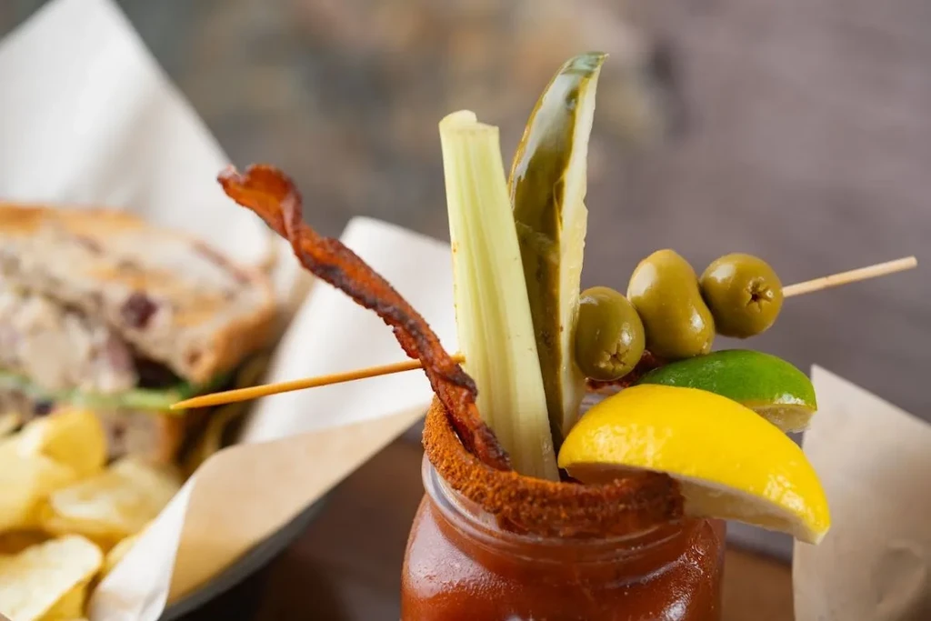Garnished Bloody Mary in a mason jar with bacon, celery, pickle, olives.