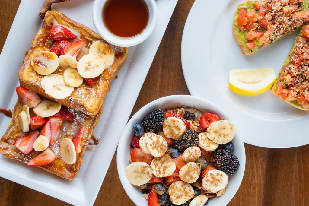 Overhead breakfast spread featuring French toast, oatmeal, and avocado toast.