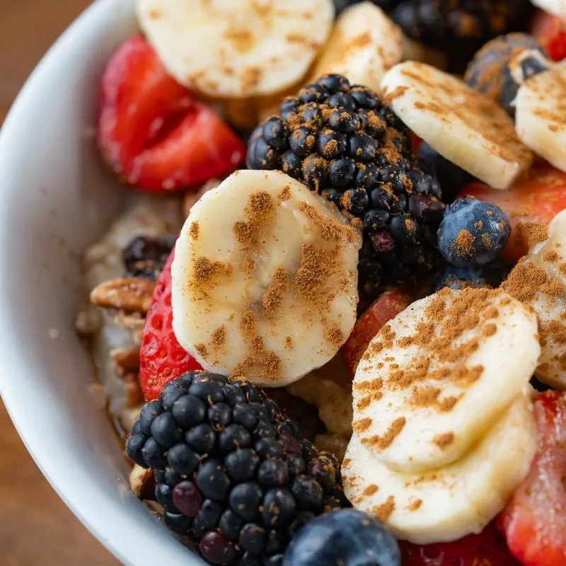 Mixed fruit bowl with strawberries, blueberries, banana, and granola.