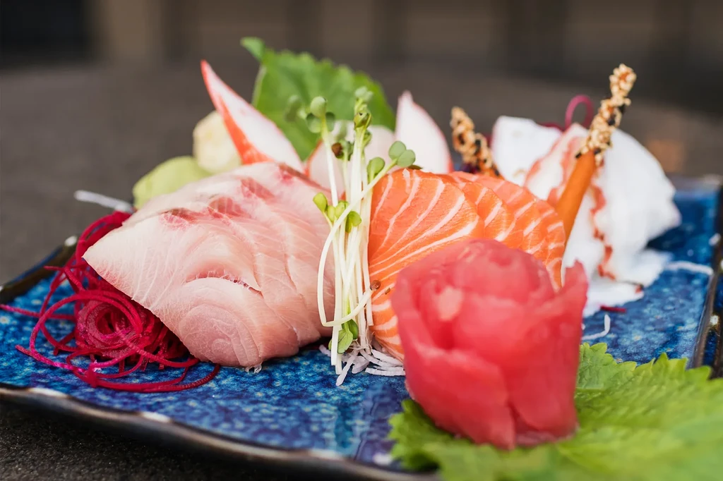 Artfully arranged sashimi platter with salmon, snapper, ginger, and sprouts.