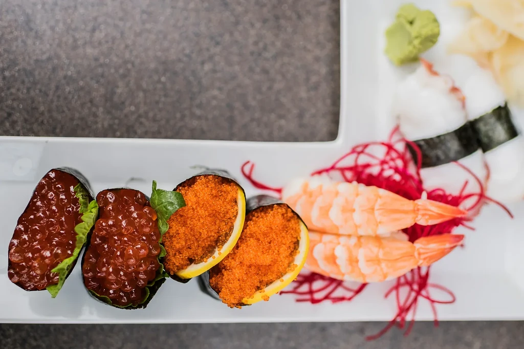 Assortment of sushi and sashimi on a white, sectioned plate.