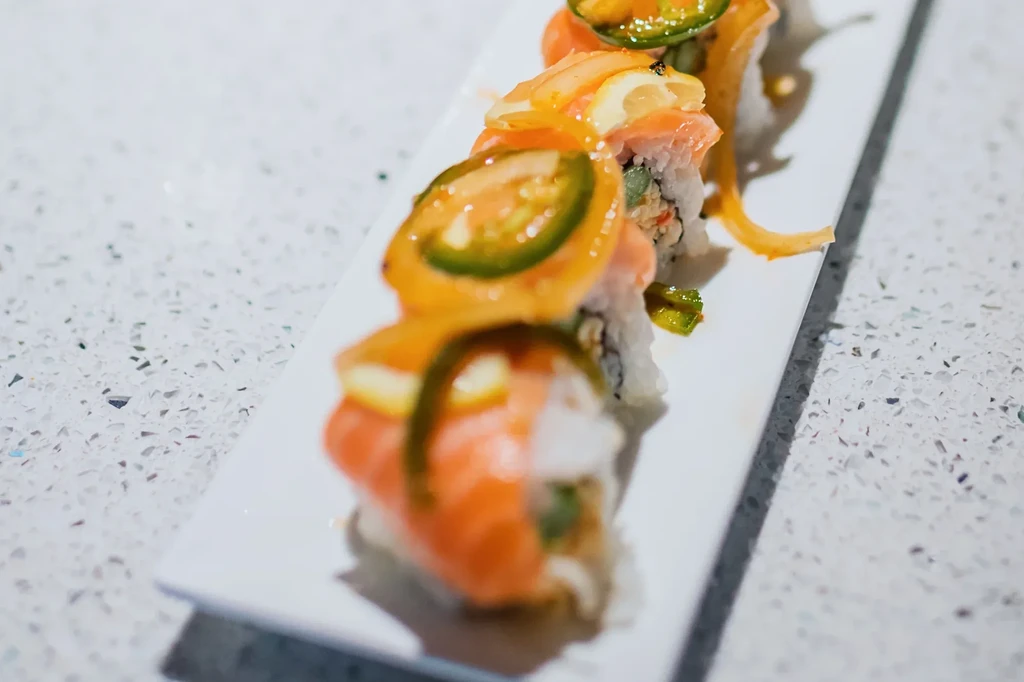 Close-up sushi roll with jalapeño, preserved lemon, and orange sauce.