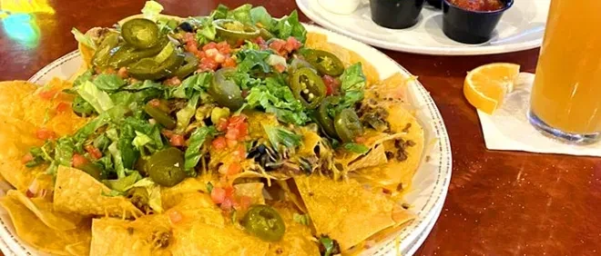 Nachos piled high with cheese, meat, lettuce, tomatoes, and jalapeños.