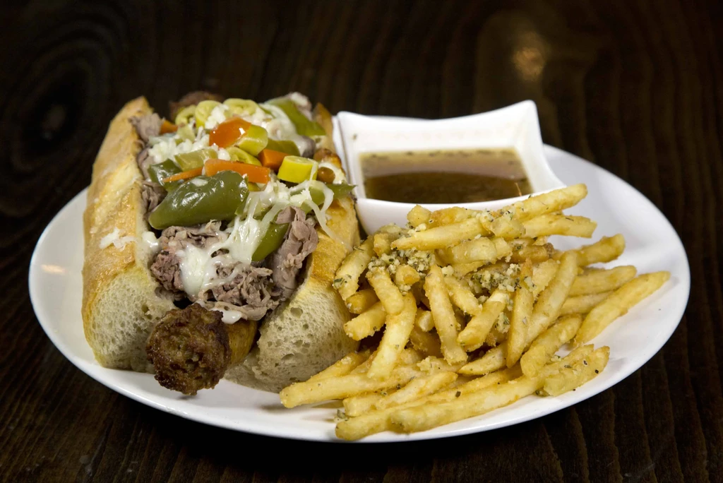 Steak sandwich with pickled vegetables, fries, and dipping sauce.