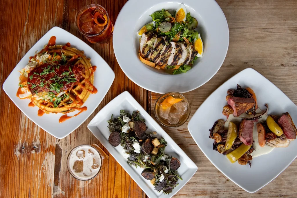 Overhead view: various gourmet dishes and drinks on a rustic table.