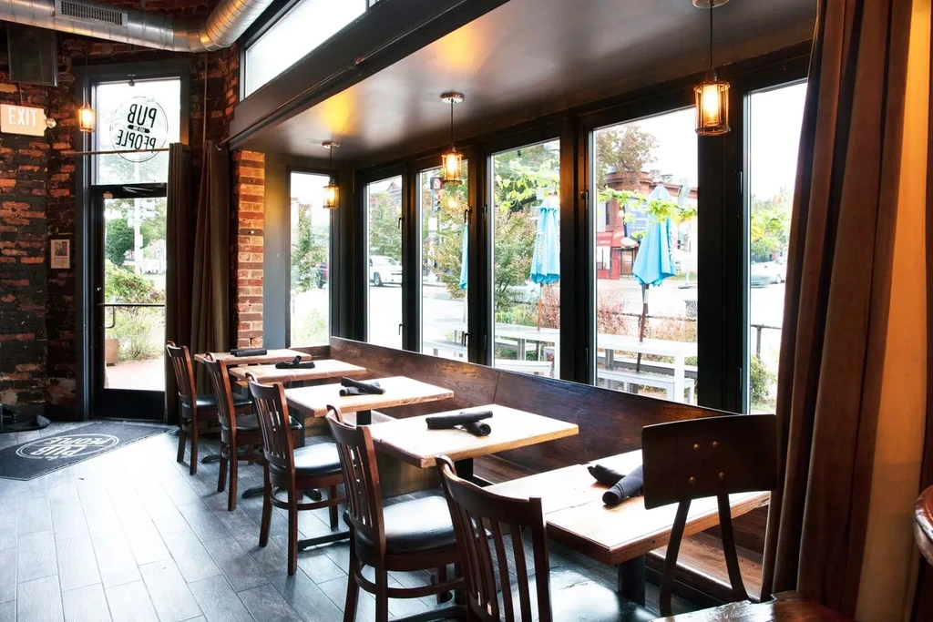 Empty pub interior with window seats, exposed brick, and industrial decor.