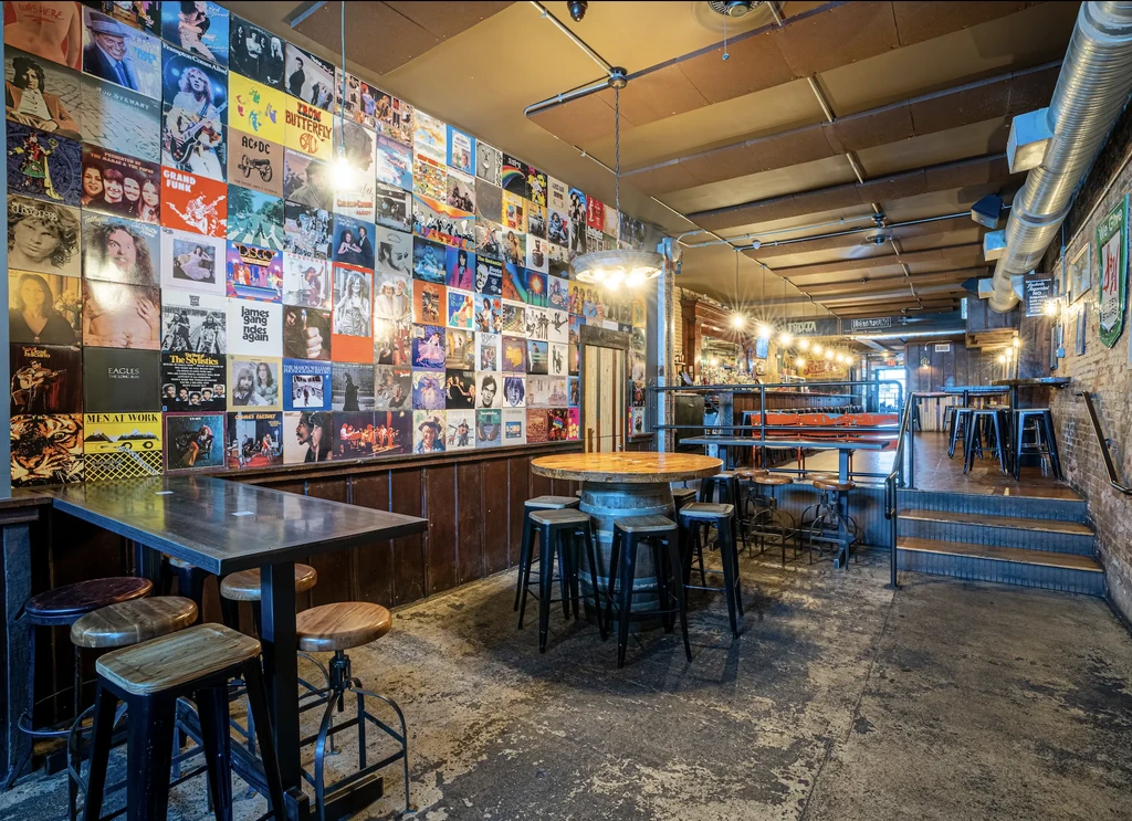 Empty, music-themed bar interior with a large vintage album cover wall.