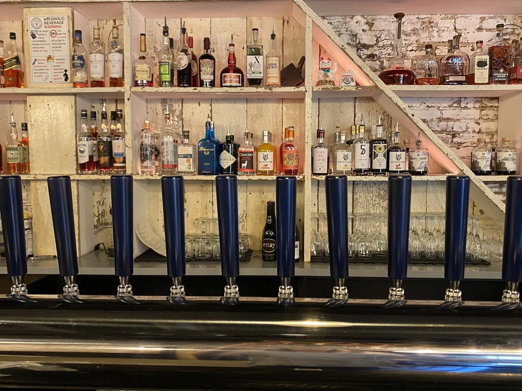 Rustic, well-stocked bar from a patron's view with taps and spirits.