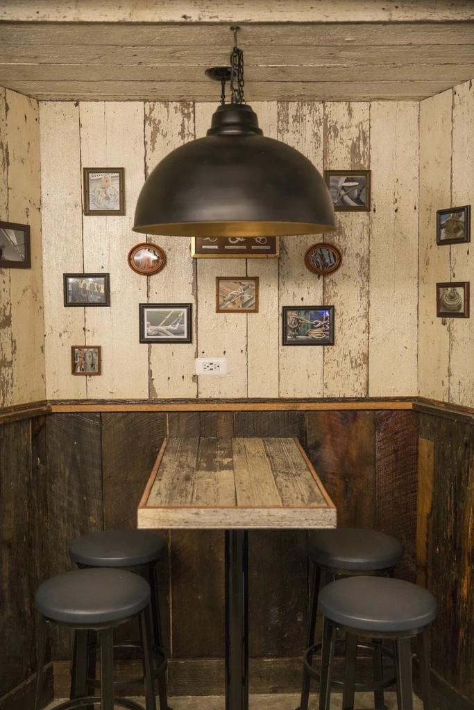 Rustic restaurant corner with high-top table, stools, and metallic dome light.