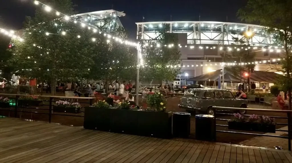 Outdoor night gathering with string lights, blurred people, and modern building.