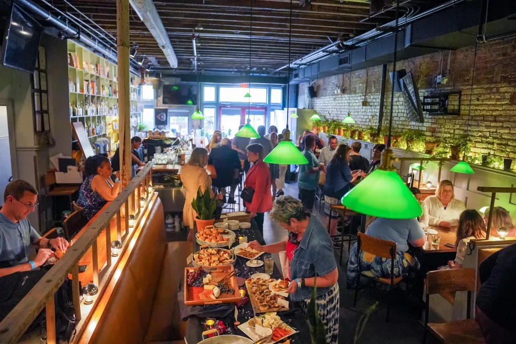 Lively restaurant event with buffet, mingling guests, and green dome lights.