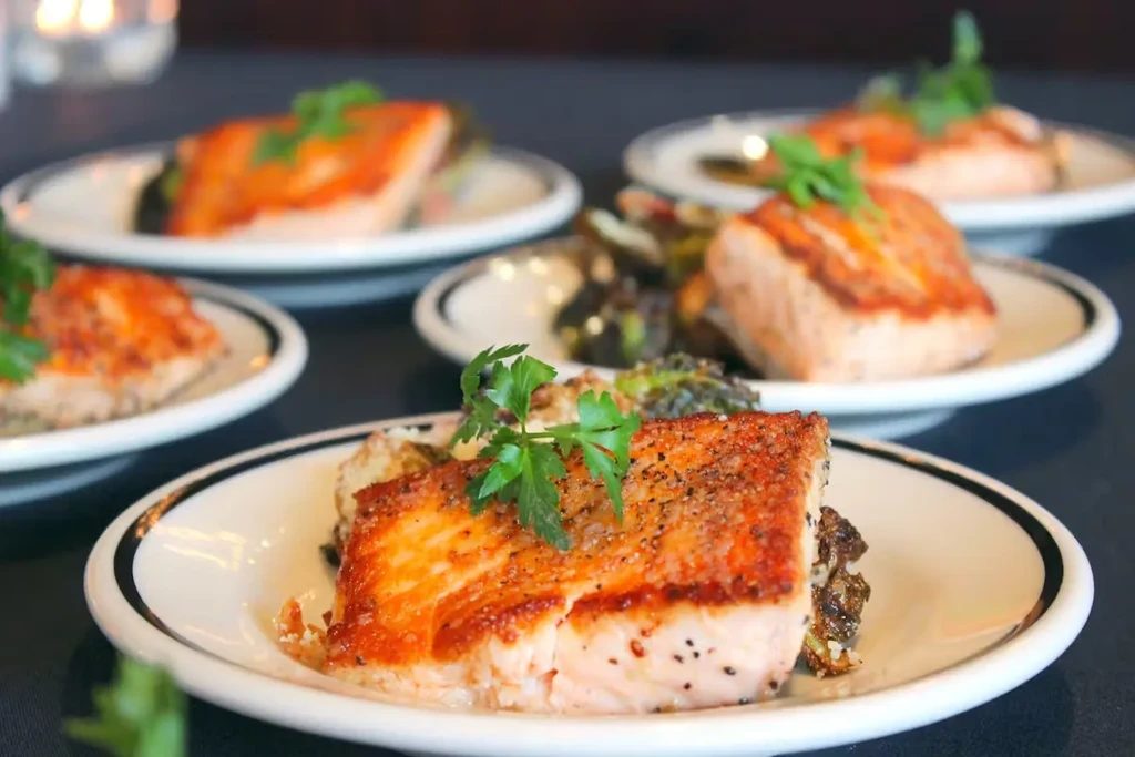 Seared salmon fillet with crispy skin, parsley, and roasted vegetables.