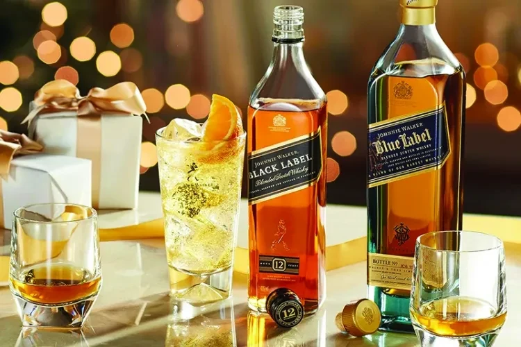 Two Johnnie Walker whisky bottles, drinks, and blurred gift boxes.