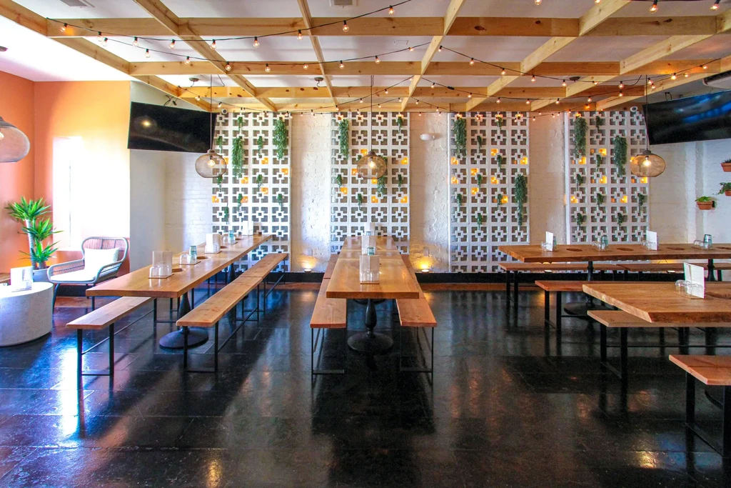 Modern restaurant interior with communal tables, string-lit ceiling, and patterned walls.