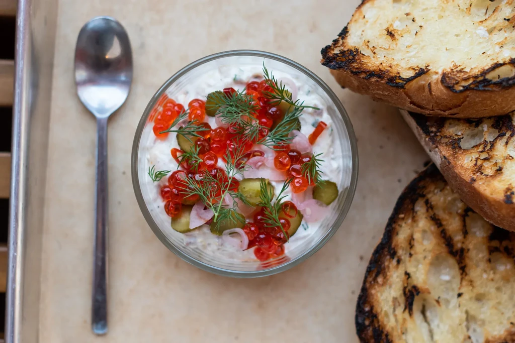 Gourmet appetizer: salmon roe, creamy dip, gherkins, dill, charred toast.