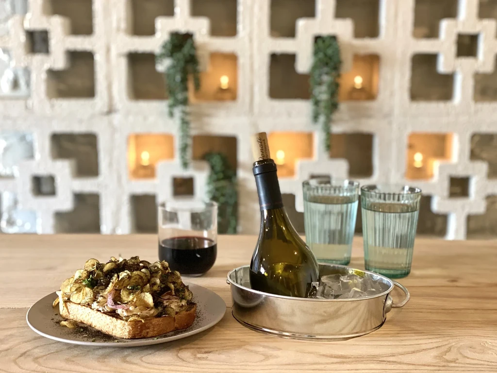 Open-faced sandwich, red wine, and chilled bottle in a modern restaurant.