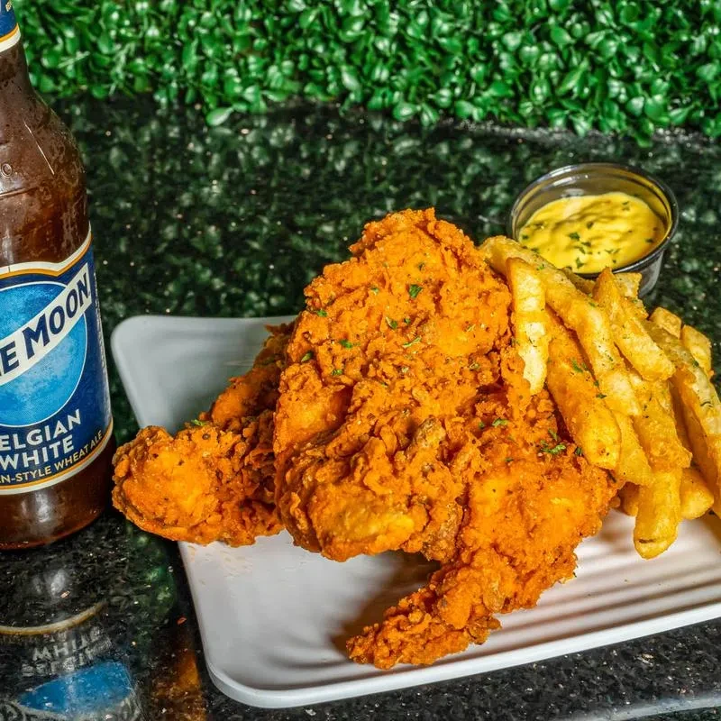 Plate of crispy fried chicken, fries, sauce, and Blue Moon beer.