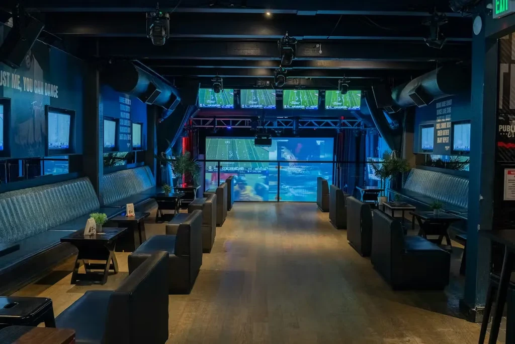 Empty modern sports bar with blue lighting and multiple sports screens.