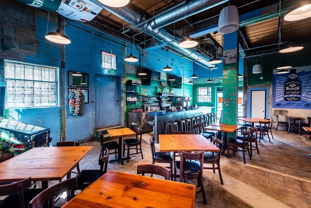 Empty industrial bar with blue walls, metallic counter, and a pinball machine.