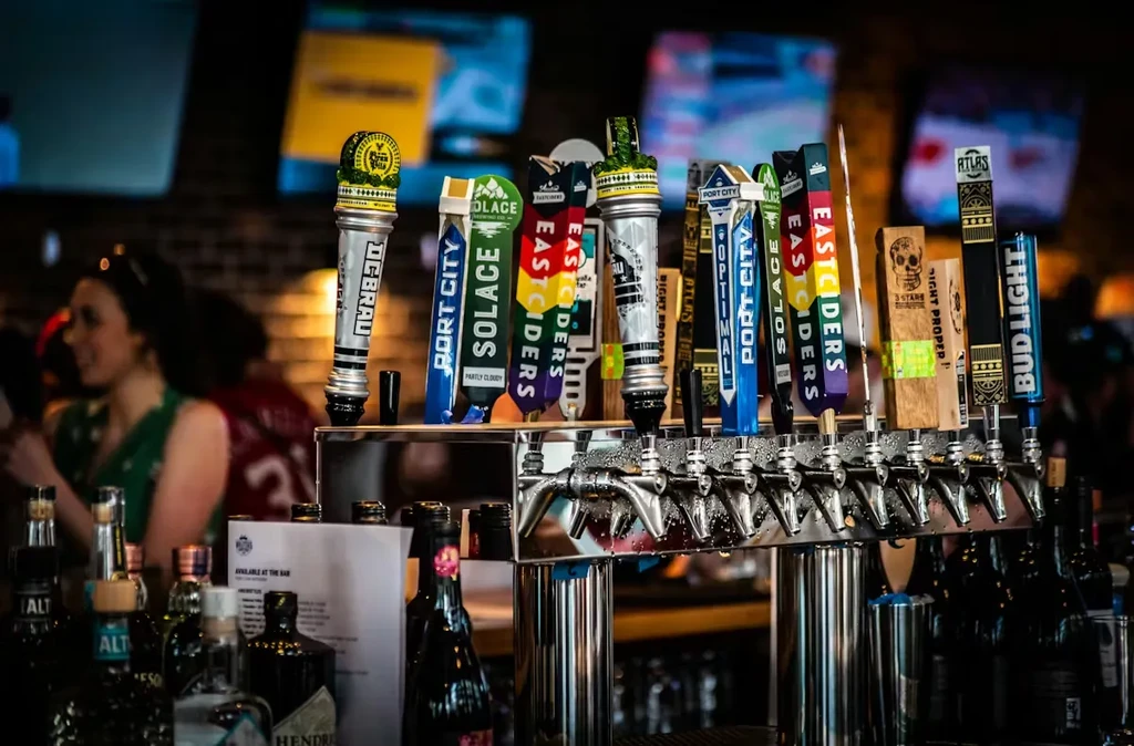 Close-up of colorful branded beer taps in a dimly lit bar.
