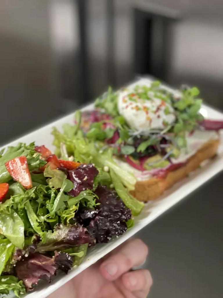 Colorful salad with strawberries and toast with a poached egg on a plate.
